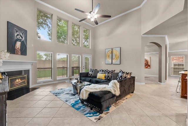 2512 Garnetfield Ln, Friendswood, TX 77546 - living room with crown molding, ceiling fan, light tile patterned flooring, arched walkways, and a glass covered fireplace