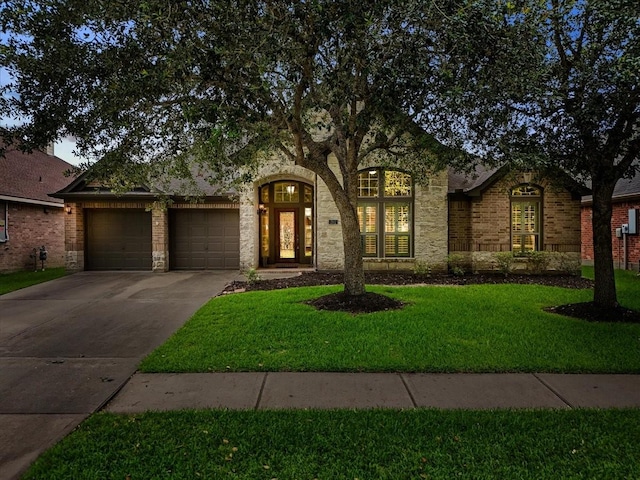 2512 Garnetfield Ln, Friendswood, TX 77546 - view of front of property featuring an attached garage, driveway, a front yard, and stone siding
