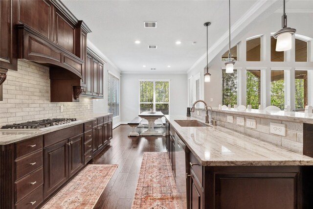 315 Lagarto Way, Pinehurst, TX 77362 - kitchen featuring a sink, stainless steel gas stovetop, ornamental molding, backsplash, and dark wood-style flooring