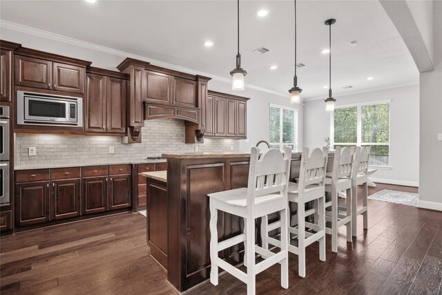 315 Lagarto Way, Pinehurst, TX 77362 - kitchen featuring appliances with stainless steel finishes, decorative backsplash, dark wood-style floors, a kitchen breakfast bar, and decorative light fixtures