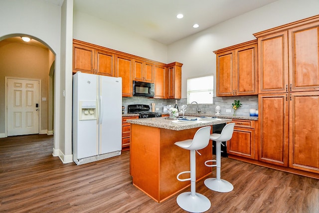 20722 Raven Mist Ct, Katy, TX 77449 - kitchen featuring black appliances, dark wood-style flooring, a center island, tasteful backsplash, and recessed lighting