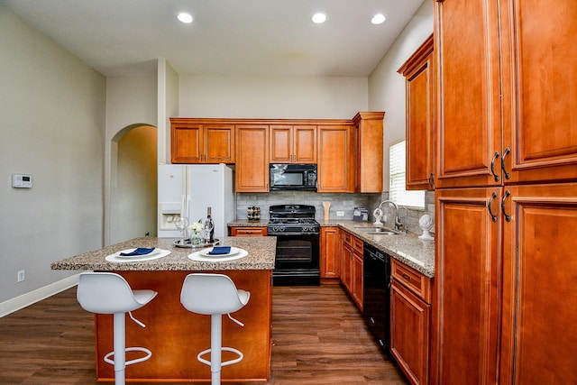 20722 Raven Mist Ct, Katy, TX 77449 - kitchen featuring black appliances, a sink, arched walkways, a center island, and tasteful backsplash