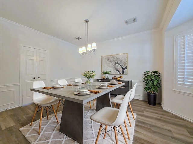 6415 Taimer Ct, Sugar Land, TX 77479 - dining area featuring wood finished floors, a chandelier, ornamental molding, a wainscoted wall, and a decorative wall
