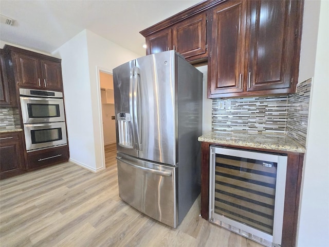 6415 Taimer Ct, Sugar Land, TX 77479 - kitchen featuring appliances with stainless steel finishes, beverage cooler, light wood-style floors, decorative backsplash, and light stone counters