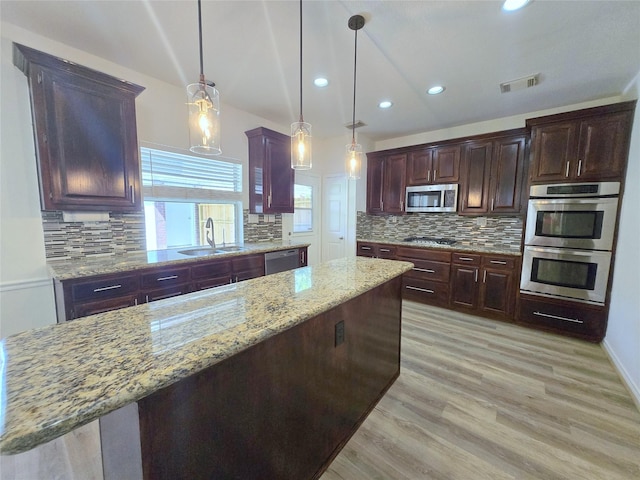 6415 Taimer Ct, Sugar Land, TX 77479 - kitchen featuring stainless steel appliances, a sink, backsplash, light wood-style flooring, and light stone counters