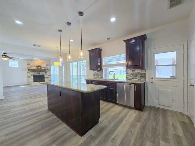 6415 Taimer Ct, Sugar Land, TX 77479 - kitchen with dishwasher, a sink, light wood-style floors, a stone fireplace, and a kitchen island