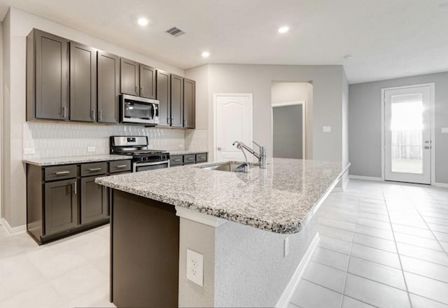 4827 Austin Meadow Ln, Katy, TX 77449 - kitchen with stainless steel appliances, a sink, an island with sink, light stone counters, and baseboards