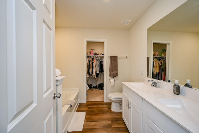 4611 Prairie Chase Dr, Houston, TX 77069 - bathroom featuring a walk in closet, double vanity, a garden tub, toilet, and wood finished floors
