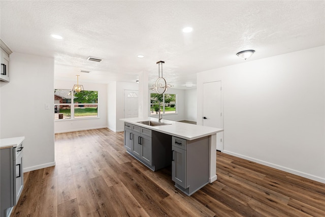 7815 Brook Trail Cir, Houston, TX 77040 - kitchen with gray cabinetry, a sink, dark wood finished floors, light countertops, and a center island with sink