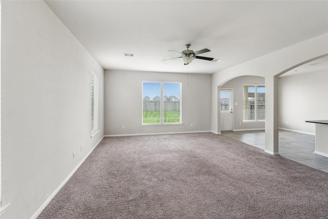 8014 Oxbow Manor Ln, Cypress, TX 77433 - unfurnished room featuring arched walkways, ceiling fan, carpet floors, baseboards, and tile patterned flooring