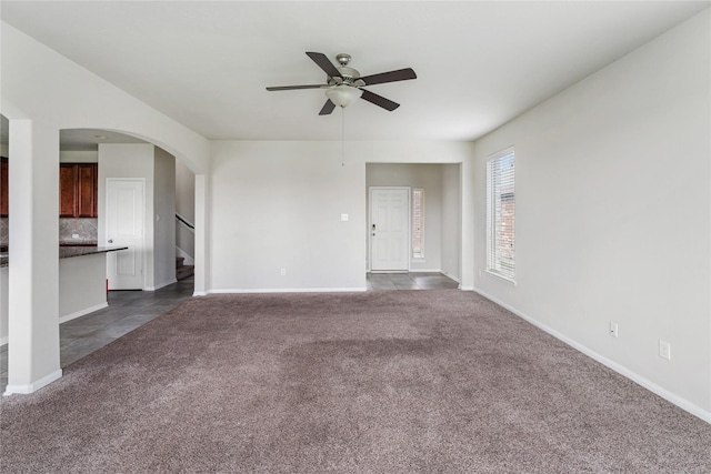 8014 Oxbow Manor Ln, Cypress, TX 77433 - unfurnished living room featuring a ceiling fan, dark colored carpet, arched walkways, stairway, and baseboards