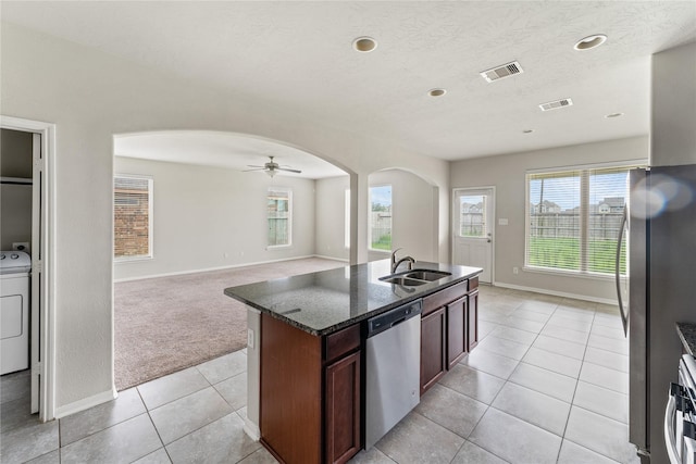 8014 Oxbow Manor Ln, Cypress, TX 77433 - kitchen featuring appliances with stainless steel finishes, arched walkways, a sink, washer / clothes dryer, and dark stone counters