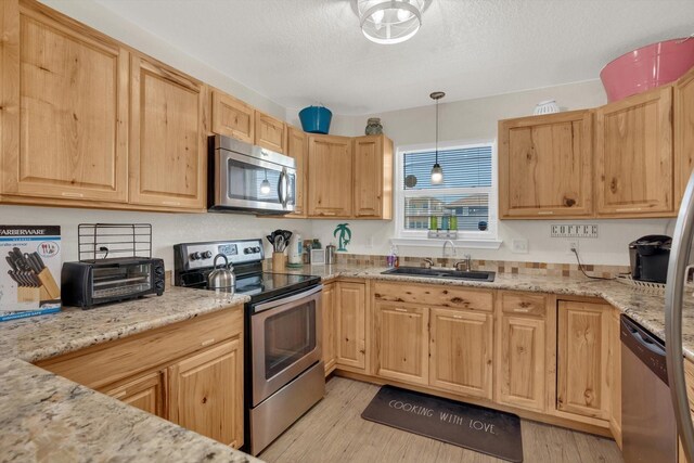 123 Howard Ave, Surfside Beach, TX 77541 - kitchen with stainless steel appliances, a sink, light brown cabinets, light wood-style floors, and a textured ceiling
