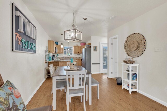 123 Howard Ave, Surfside Beach, TX 77541 - dining area featuring a chandelier, light wood-type flooring, and baseboards