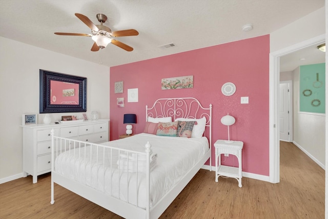 123 Howard Ave, Surfside Beach, TX 77541 - bedroom with light wood-style flooring, baseboards, a ceiling fan, and an accent wall