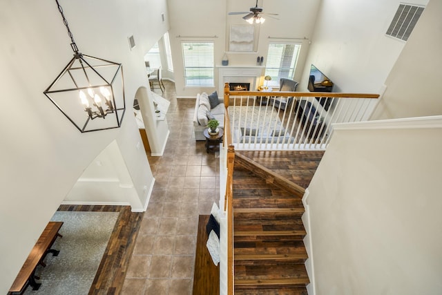 20918 Normandy Forest Dr, Spring, TX 77388 - staircase featuring a ceiling fan, a warm lit fireplace, baseboards, tile patterned floors, and a chandelier