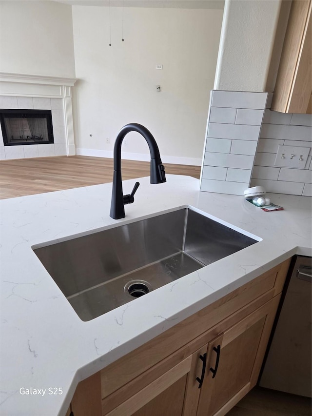 16111 Aberdeen Forest Dr, Houston, TX 77095 - kitchen view of a sink, light stone counters, backsplash, dark wood-style flooring, and a fireplace