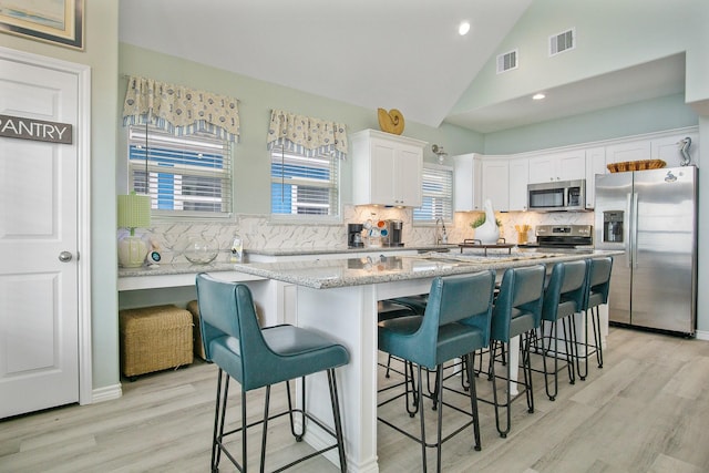 1214 Hwy 87, Gilchrist, TX 77617 - kitchen with appliances with stainless steel finishes, white cabinetry, tasteful backsplash, light wood-style floors, and recessed lighting