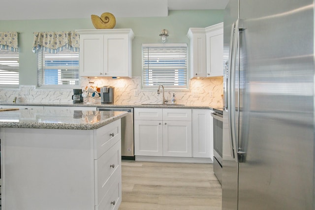 1214 Hwy 87, Gilchrist, TX 77617 - kitchen with stainless steel appliances, a sink, white cabinets, and light wood-style floors