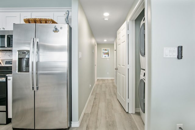 1214 Hwy 87, Gilchrist, TX 77617 - kitchen with stainless steel appliances, stacked washer / drying machine, light wood finished floors, white cabinetry, and baseboards
