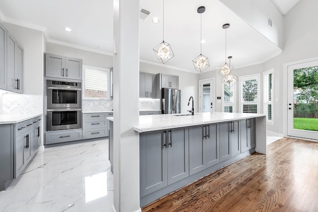 8903 Loch Lomond Ct, Houston, TX 77096 - kitchen with gray cabinets, appliances with stainless steel finishes, backsplash, a large island with sink, and recessed lighting