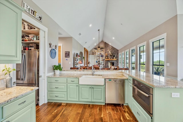 1932 Chappell Ridge Ln, Chappell Hill, TX 77426 - kitchen featuring green cabinetry, appliances with stainless steel finishes, a stone fireplace, dark wood finished floors, and lofted ceiling
