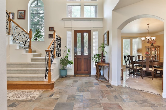 2107 N Shadow Grove Ln, Richmond, TX 77406 - entryway featuring arched walkways, a chandelier, stairs, a high ceiling, and stone tile flooring