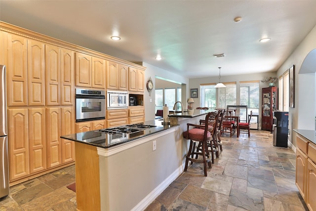 2107 N Shadow Grove Ln, Richmond, TX 77406 - kitchen with stainless steel appliances, stone tile flooring, a kitchen bar, light brown cabinetry, and recessed lighting
