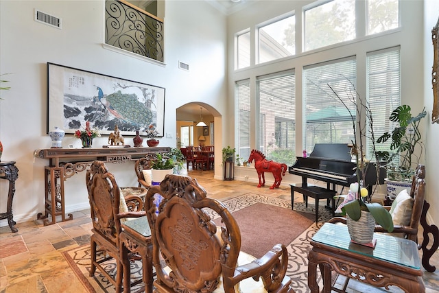 2107 N Shadow Grove Ln, Richmond, TX 77406 - living room with arched walkways, a towering ceiling, baseboards, stone tile floors, and crown molding