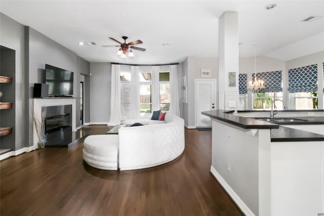 2902 Sycamore Tree Ct, Houston, TX 77345 - living room featuring a glass covered fireplace, dark wood-type flooring, a ceiling fan, a chandelier, and baseboards