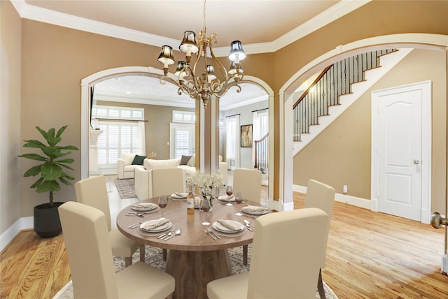 1210 Crocker St, Houston, TX 77019 - dining space with arched walkways, light wood-type flooring, stairs, crown molding, and a chandelier