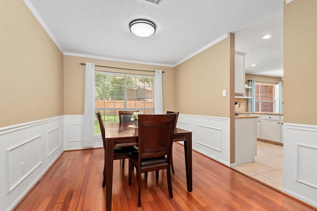 3802 Sweetgum Hill Ln, Kingwood, TX 77345 - dining space featuring a wainscoted wall, ornamental molding, a decorative wall, and light wood-type flooring