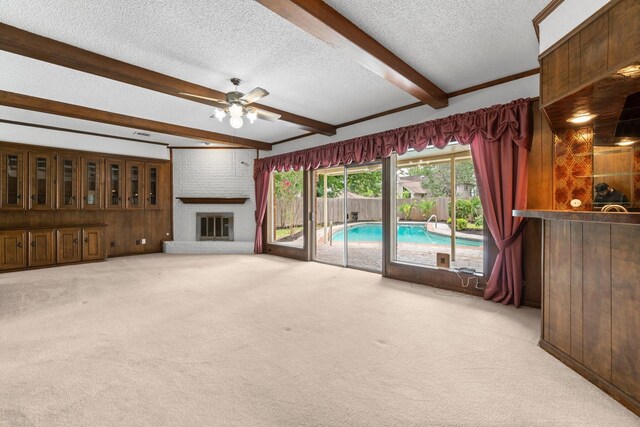 6623 Coral Ridge Rd, Houston, TX 77069 - unfurnished living room with light colored carpet, a textured ceiling, ceiling fan, beam ceiling, and a fireplace