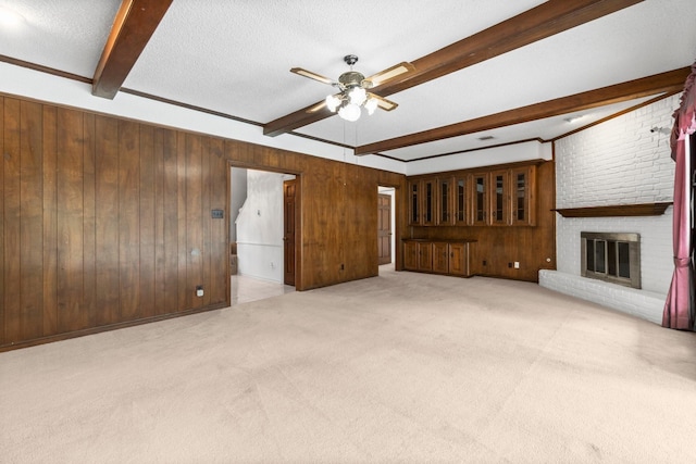 6623 Coral Ridge Rd, Houston, TX 77069 - unfurnished living room with beamed ceiling, a ceiling fan, carpet flooring, wood walls, and a fireplace