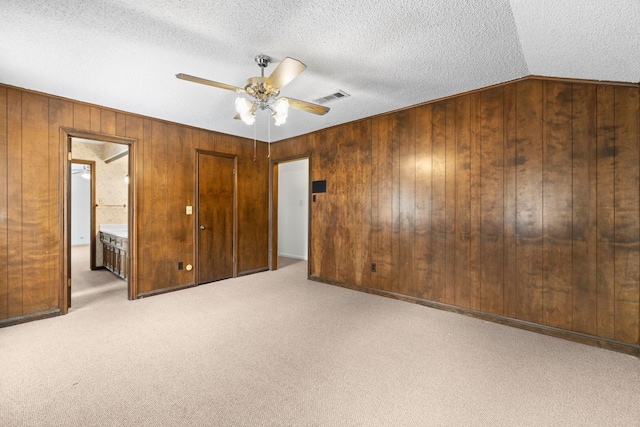 6623 Coral Ridge Rd, Houston, TX 77069 - unfurnished bedroom featuring wood walls, a textured ceiling, carpet flooring, ensuite bath, and ceiling fan