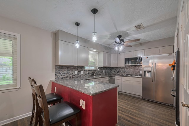 15726 Blackhawk Blvd, Friendswood, TX 77546 - kitchen featuring stainless steel appliances, a peninsula, decorative backsplash, dark wood-style floors, and a textured ceiling