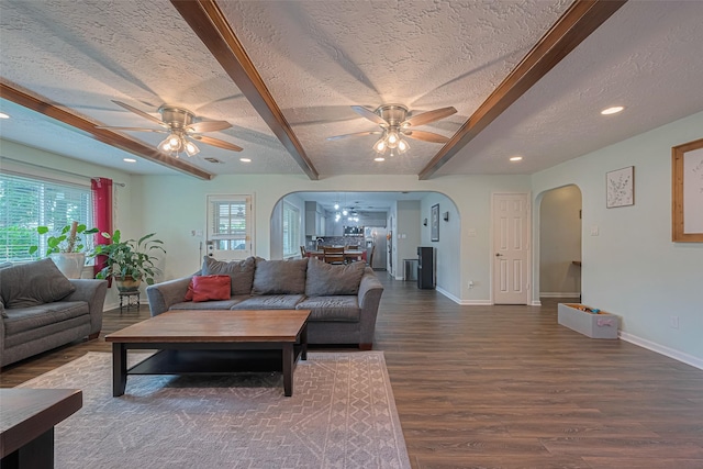 15726 Blackhawk Blvd, Friendswood, TX 77546 - living room with arched walkways, a ceiling fan, a textured ceiling, dark wood finished floors, and beamed ceiling