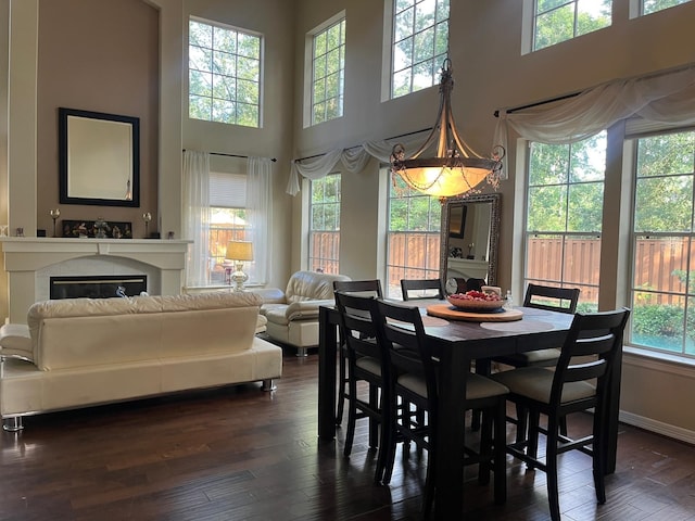 3 Candle Pine Pl, The Woodlands, TX 77381 - dining area featuring dark wood-style flooring, a towering ceiling, a glass covered fireplace, and baseboards