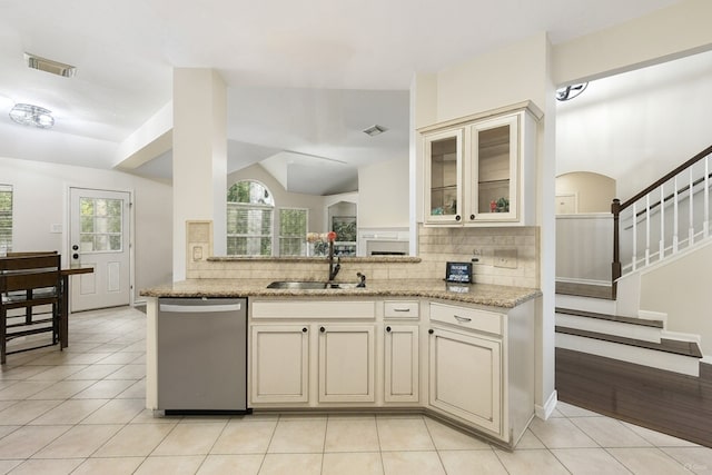 38 Florian Ct, Conroe, TX 77385 - kitchen featuring stainless steel dishwasher, a sink, cream cabinets, decorative backsplash, and vaulted ceiling