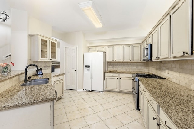 38 Florian Ct, Conroe, TX 77385 - kitchen with stainless steel appliances, a sink, decorative backsplash, light stone counters, and cream cabinets