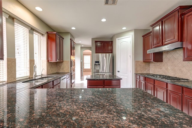 17215 Astrachan Rd, Richmond, TX 77407 - kitchen featuring appliances with stainless steel finishes, a sink, arched walkways, under cabinet range hood, and recessed lighting