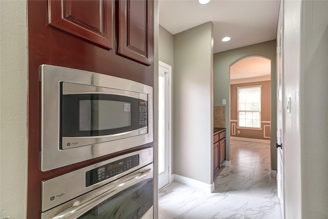 17215 Astrachan Rd, Richmond, TX 77407 - kitchen with appliances with stainless steel finishes, light marble finish floors, arched walkways, baseboards, and recessed lighting