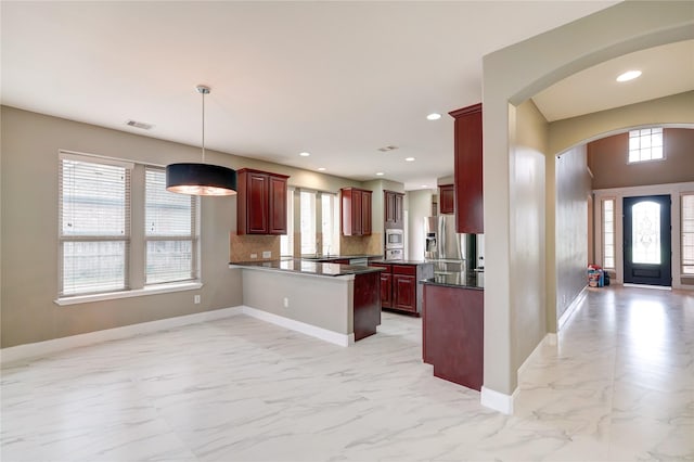 17215 Astrachan Rd, Richmond, TX 77407 - kitchen with dark brown cabinets, appliances with stainless steel finishes, light marble finish floors, dark countertops, and arched walkways