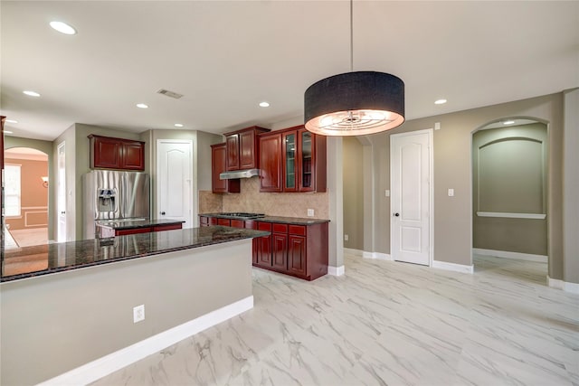 17215 Astrachan Rd, Richmond, TX 77407 - kitchen with arched walkways, stainless steel appliances, dark brown cabinets, backsplash, and recessed lighting