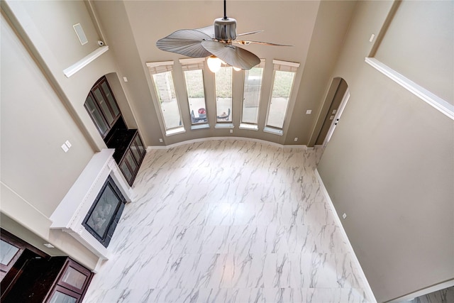 17215 Astrachan Rd, Richmond, TX 77407 - unfurnished living room featuring marble finish floors, a high ceiling, ceiling fan, and baseboards