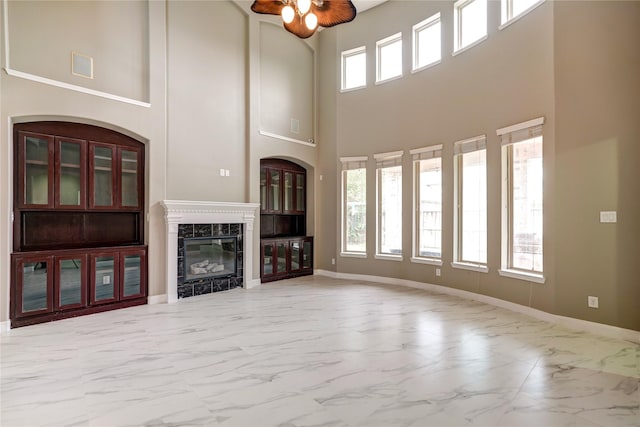 17215 Astrachan Rd, Richmond, TX 77407 - unfurnished living room with marble look tile flooring, a towering ceiling, baseboards, and a fireplace