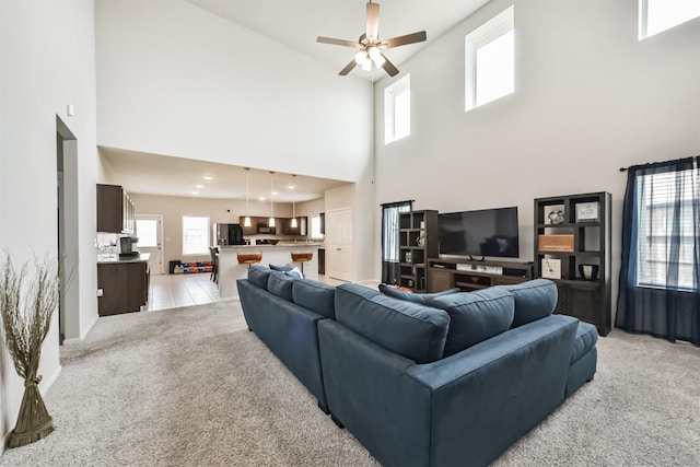 3607 Crosspointe Pass, Angleton, TX 77515 - living area featuring light carpet, a towering ceiling, a ceiling fan, and plenty of natural light