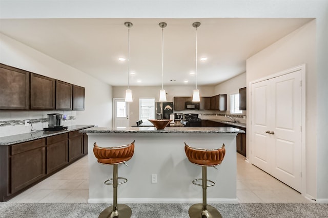 3607 Crosspointe Pass, Angleton, TX 77515 - kitchen with appliances with stainless steel finishes, dark brown cabinetry, a kitchen breakfast bar, a center island with sink, and recessed lighting