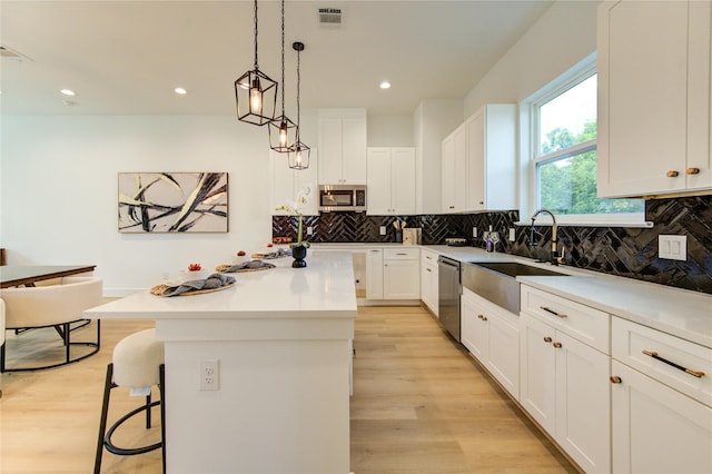 4043 Buck St, Houston, TX 77020 - kitchen featuring stainless steel appliances, a sink, light wood-style floors, a center island, and tasteful backsplash