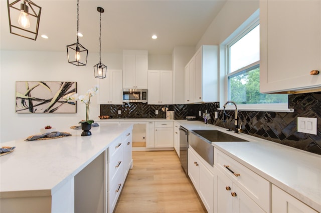 4043 Buck St, Houston, TX 77020 - kitchen featuring a sink, appliances with stainless steel finishes, white cabinetry, decorative backsplash, and pendant lighting